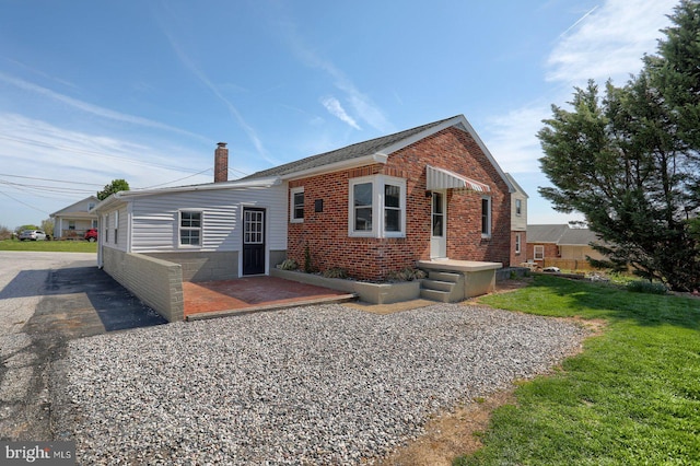 back of property with a chimney and brick siding