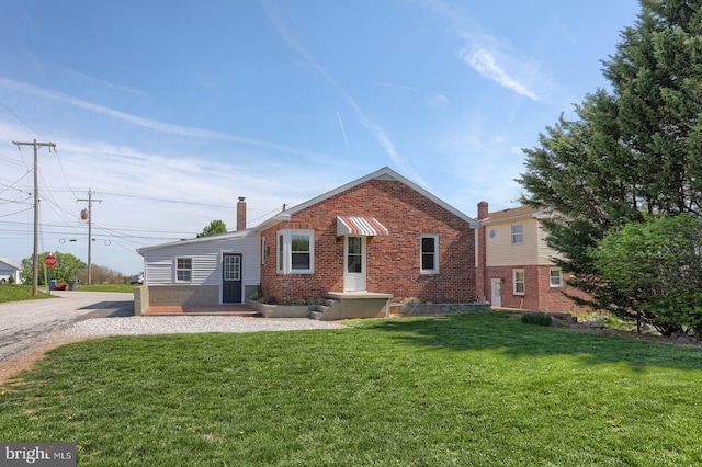 view of front of house with a front lawn, brick siding, and a chimney