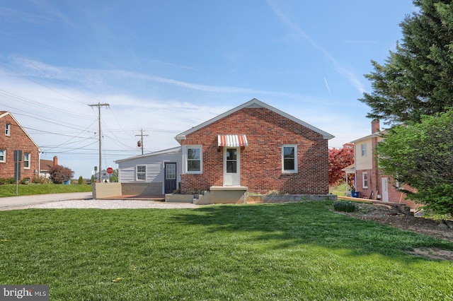 rear view of house featuring a lawn and brick siding