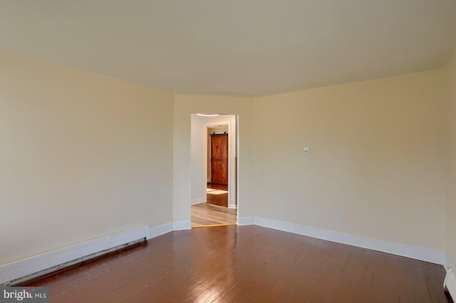 spare room with baseboard heating, baseboards, and wood-type flooring