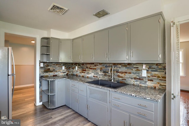 kitchen featuring freestanding refrigerator, visible vents, gray cabinetry, and a sink