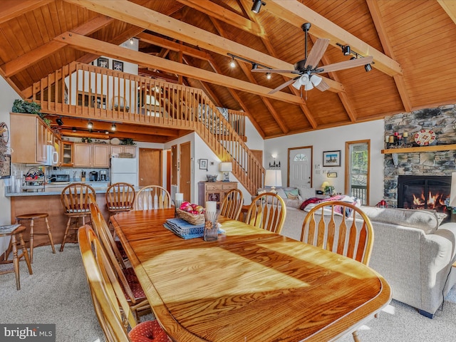 dining space featuring beamed ceiling, high vaulted ceiling, light carpet, and wooden ceiling