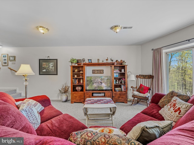 living area featuring carpet floors, baseboards, stairs, and visible vents