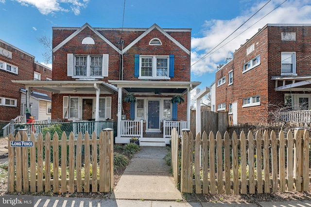 view of front of house with brick siding, a fenced front yard, and covered porch