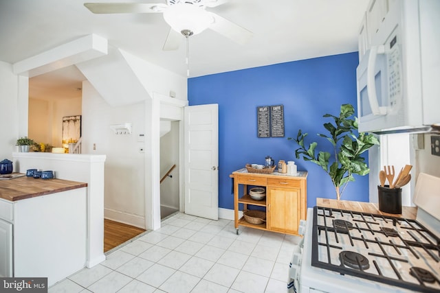 kitchen with a ceiling fan, wooden counters, baseboards, white cabinets, and white appliances