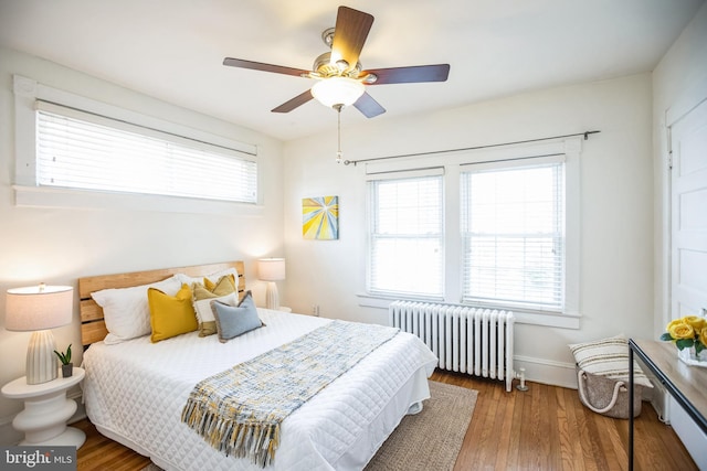 bedroom featuring radiator, baseboards, a ceiling fan, and wood finished floors