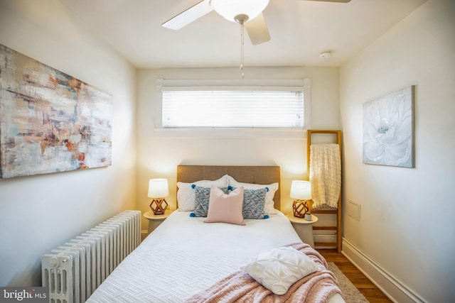 bedroom featuring a ceiling fan, baseboards, radiator heating unit, and wood finished floors