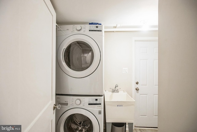 laundry room featuring a sink, stacked washer / drying machine, and laundry area