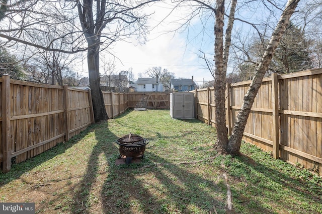 view of yard with a fenced backyard, an outdoor fire pit, and a shed