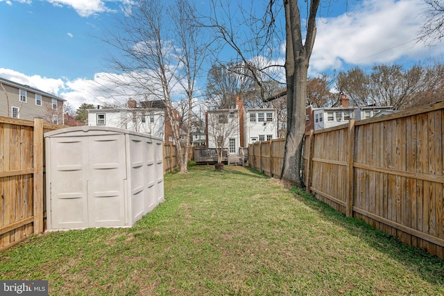 view of yard with a storage unit, a fenced backyard, and a residential view