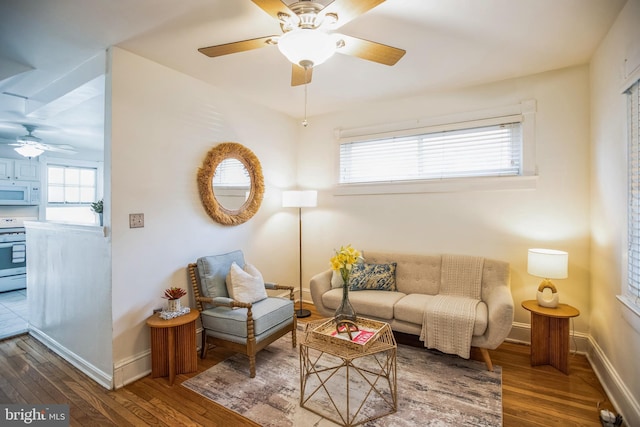 living area with baseboards, a ceiling fan, hardwood / wood-style flooring, and a wealth of natural light