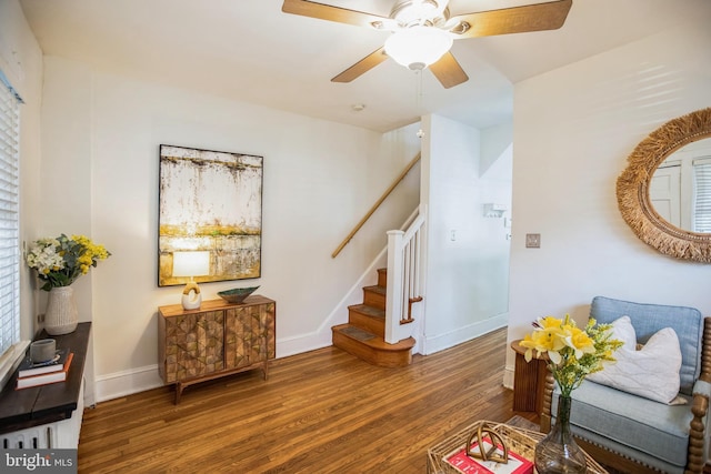 sitting room featuring stairway, baseboards, a ceiling fan, and wood finished floors