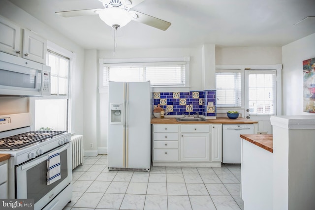 kitchen featuring white appliances, ceiling fan, white cabinets, a sink, and wood counters