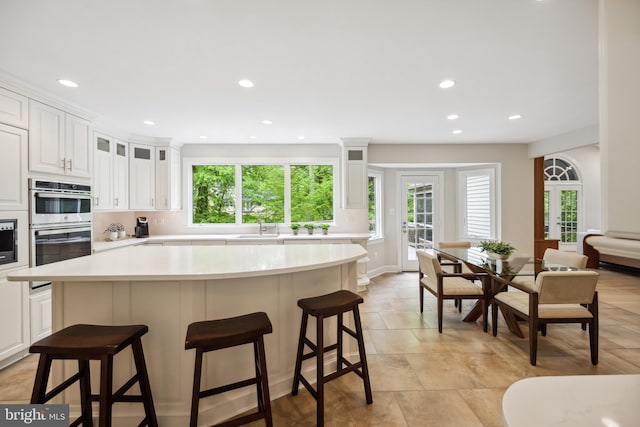 6530 Heather Brook Ct, Mclean, VA 22101 - kitchen with light countertops, recessed lighting, stainless steel double oven, and a kitchen bar