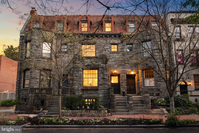 view of front of house featuring a chimney and stone siding