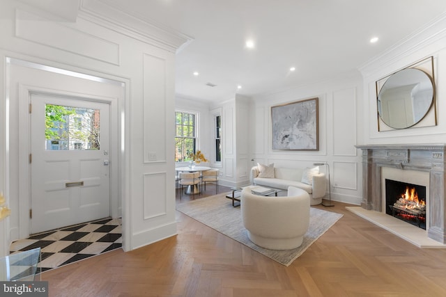 foyer entrance featuring crown molding, a high end fireplace, a decorative wall, and recessed lighting