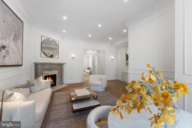 living room featuring a premium fireplace, recessed lighting, ornamental molding, and a decorative wall