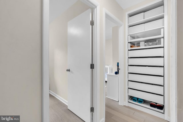 corridor featuring light wood finished floors, radiator heating unit, and baseboards