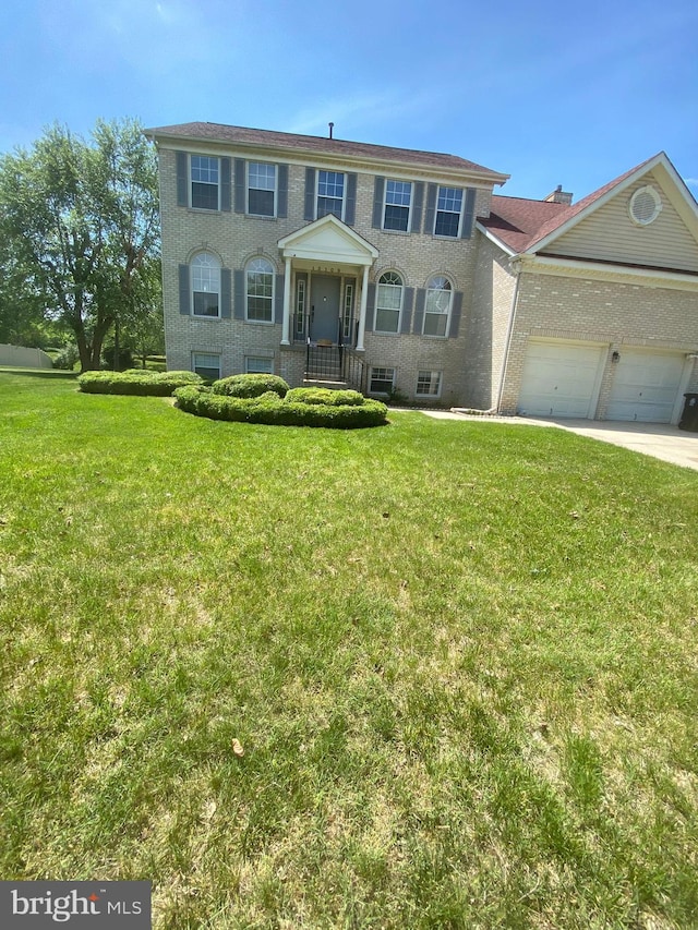 colonial house with brick siding, a front lawn, and an attached garage