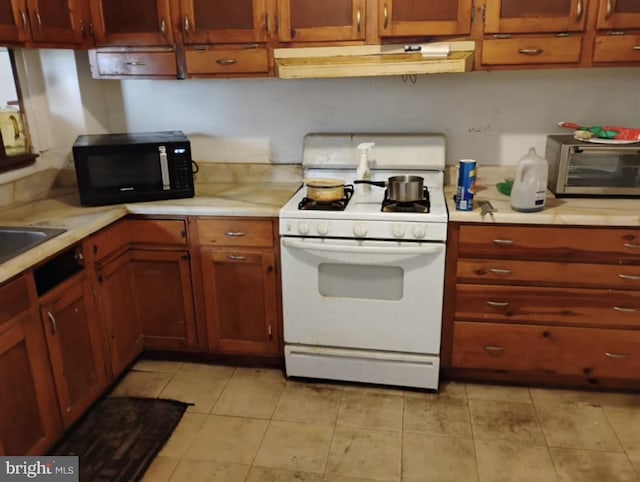 kitchen featuring white gas stove, black microwave, light countertops, and under cabinet range hood