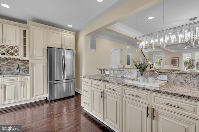 kitchen with cream cabinets, freestanding refrigerator, backsplash, dark wood-style flooring, and visible vents