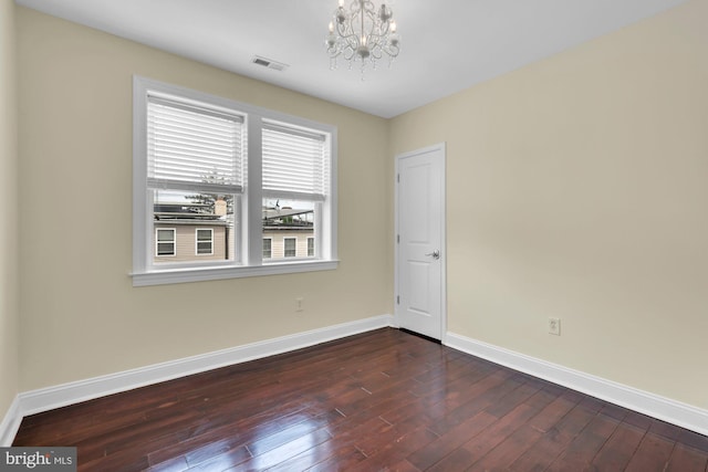 spare room with a chandelier, visible vents, dark wood-type flooring, and baseboards