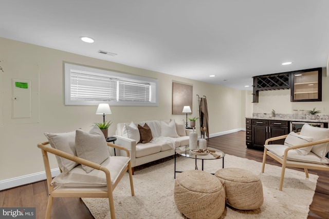 living area featuring visible vents, baseboards, recessed lighting, indoor wet bar, and dark wood-type flooring