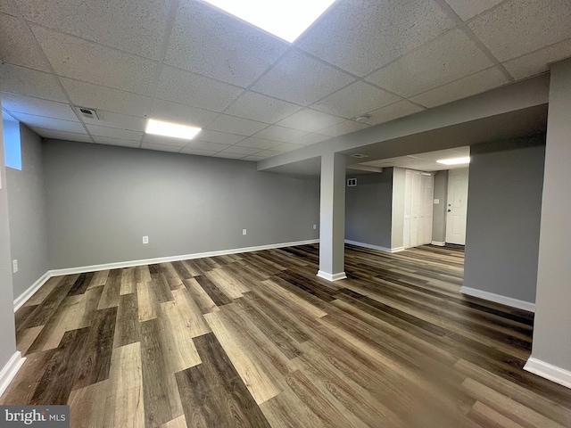 finished basement featuring baseboards, visible vents, wood finished floors, and a paneled ceiling
