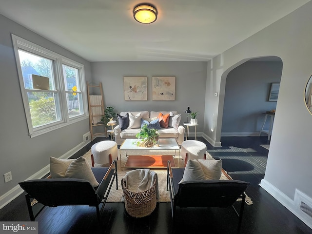 sitting room with arched walkways, visible vents, and baseboards