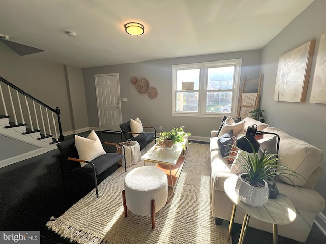 living area featuring baseboards and stairs