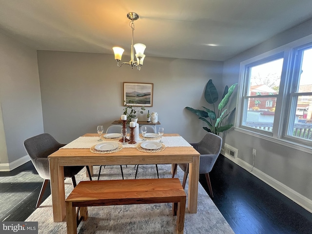 dining room featuring visible vents, baseboards, wood finished floors, and a notable chandelier