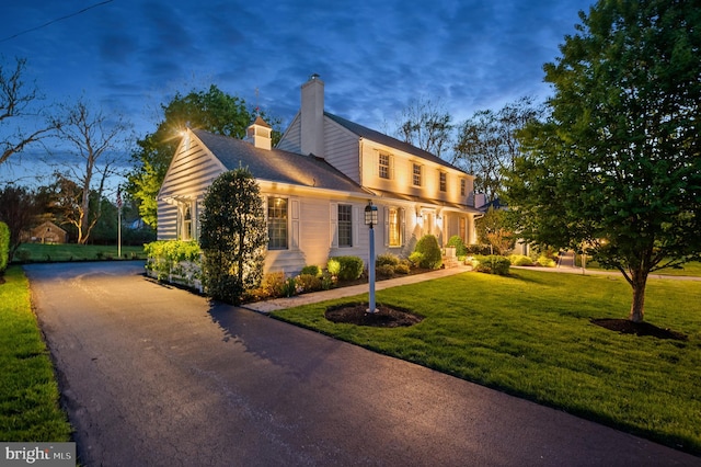 view of side of property with a yard and a chimney