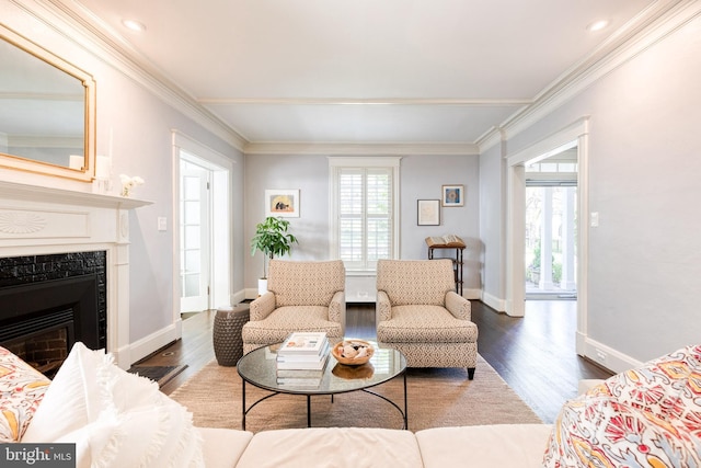 living area featuring baseboards, ornamental molding, a fireplace, and wood finished floors