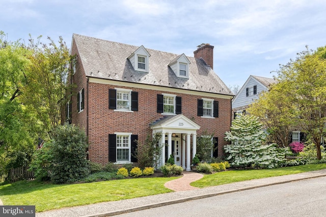 view of front of house with brick siding, a high end roof, and a chimney