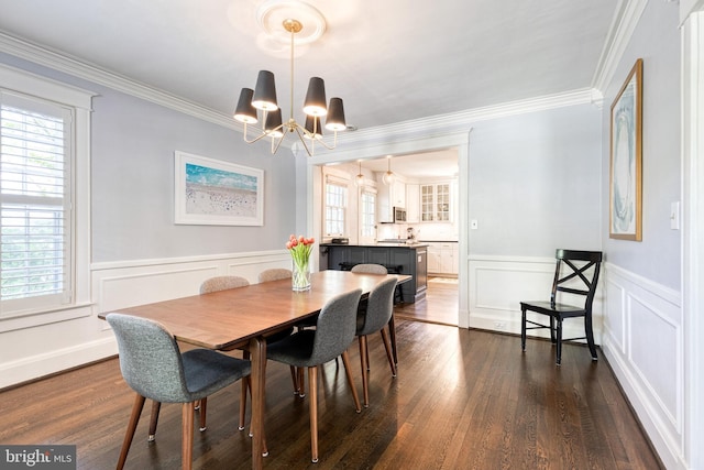 dining space featuring wainscoting, a notable chandelier, ornamental molding, and dark wood finished floors