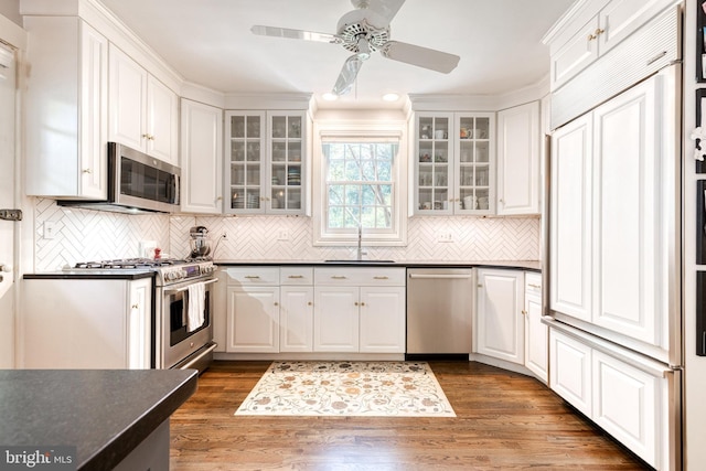 kitchen featuring dark countertops, ceiling fan, white cabinetry, a sink, and appliances with stainless steel finishes
