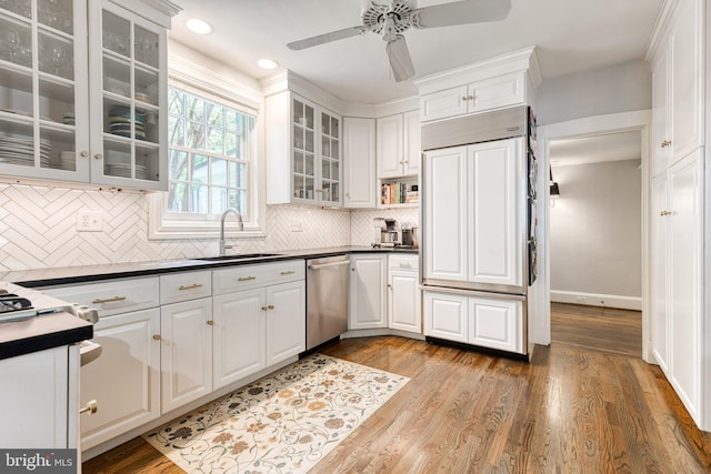 kitchen with white cabinets, paneled built in fridge, a sink, dishwasher, and a ceiling fan