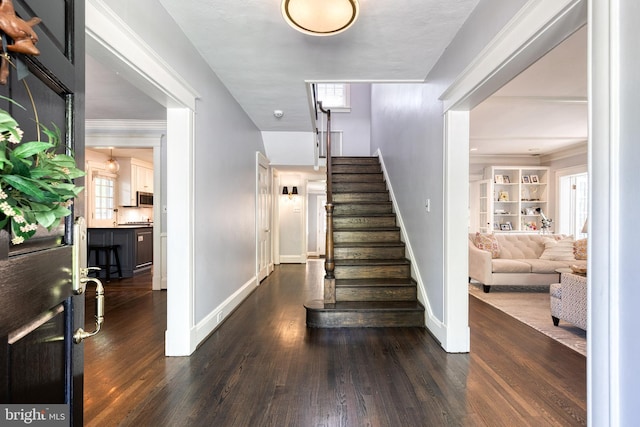foyer entrance featuring dark wood-style flooring, baseboards, and stairway