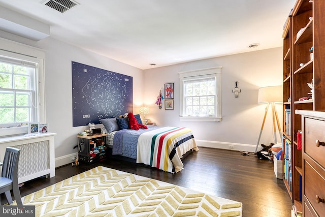 bedroom with radiator, multiple windows, dark wood-style floors, and visible vents