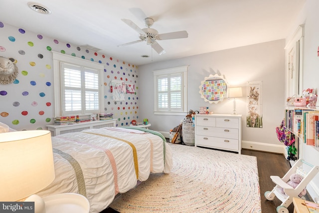bedroom featuring a ceiling fan, wallpapered walls, baseboards, visible vents, and dark wood-style floors