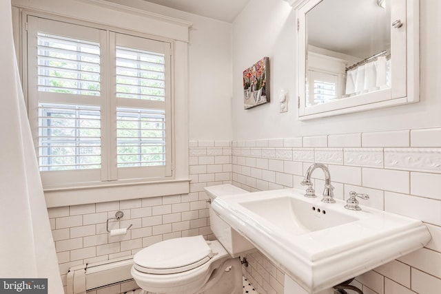 full bathroom featuring a sink, a wainscoted wall, toilet, and tile walls