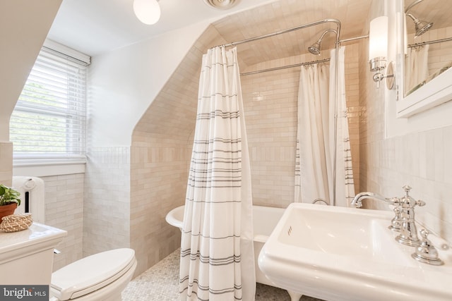 full bathroom featuring tile walls, wainscoting, a sink, toilet, and tiled shower / bath combo