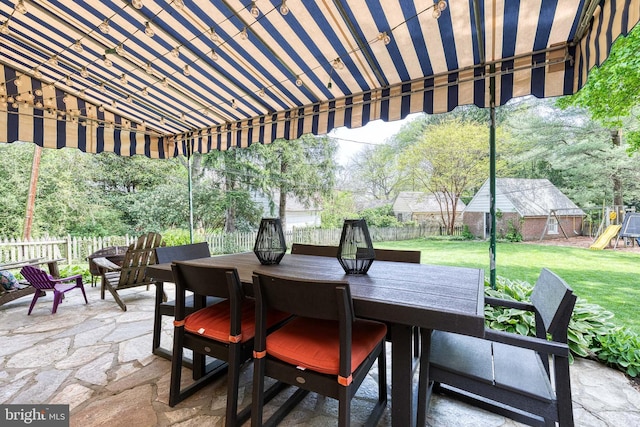 view of patio featuring a playground, outdoor dining space, and a fenced backyard