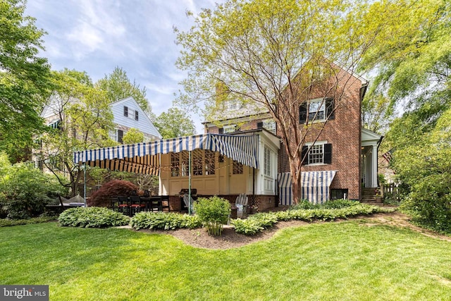 rear view of house with a lawn, a patio, and brick siding