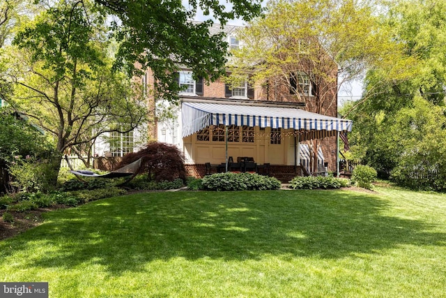 back of property with a yard and brick siding