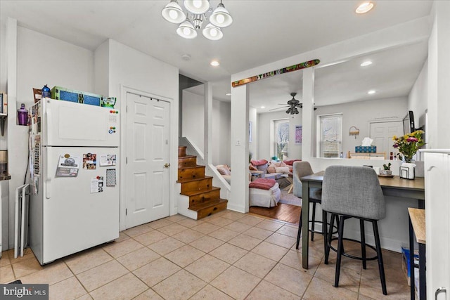 kitchen featuring light tile patterned flooring, freestanding refrigerator, recessed lighting, and ceiling fan with notable chandelier