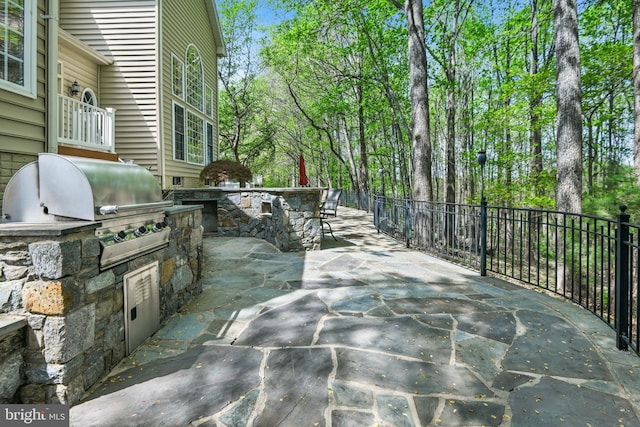 view of patio featuring an outdoor kitchen, fence, and a grill