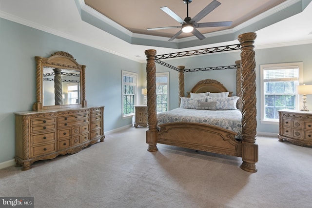 carpeted bedroom with crown molding, baseboards, ceiling fan, and a tray ceiling