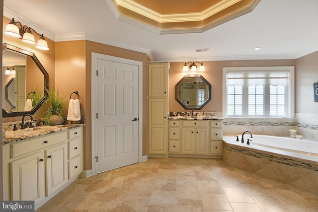 bathroom with a bath, visible vents, two vanities, ornamental molding, and a tray ceiling