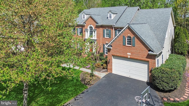 view of front of home with roof with shingles, an attached garage, aphalt driveway, and brick siding